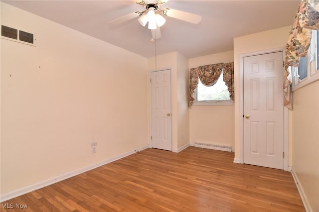 unfurnished bedroom featuring baseboards, visible vents, light wood-style flooring, and baseboard heating