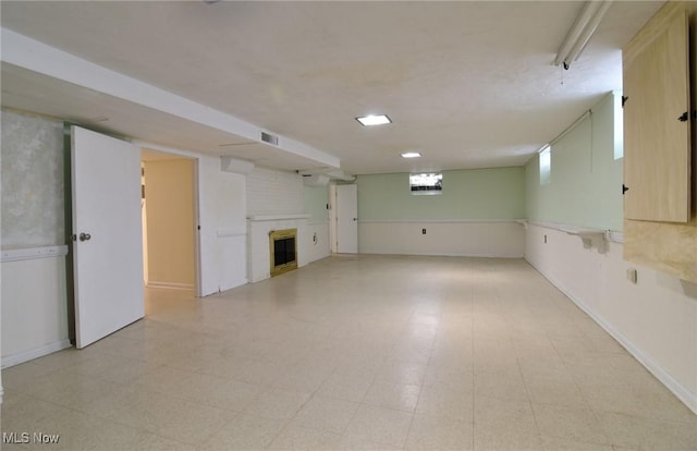 below grade area featuring a brick fireplace, visible vents, and light floors