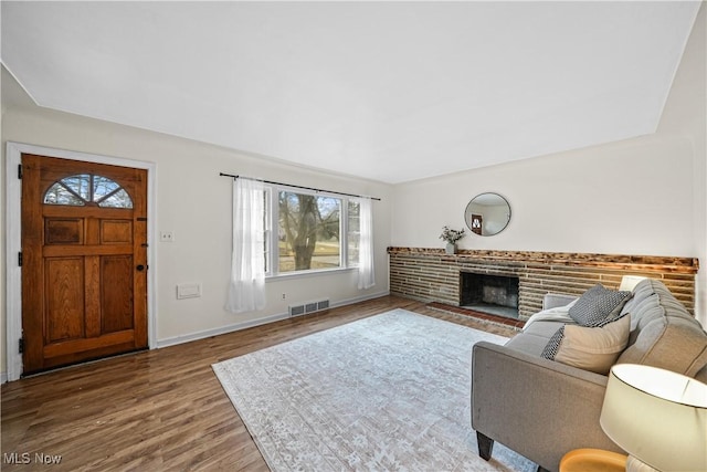 living area with baseboards, a fireplace, visible vents, and wood finished floors