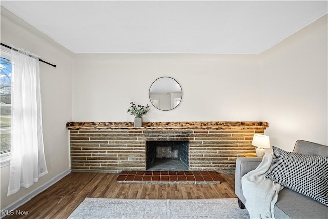 living room featuring baseboards, a tiled fireplace, and wood finished floors