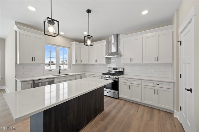 kitchen featuring appliances with stainless steel finishes, white cabinets, a kitchen island, and wall chimney exhaust hood