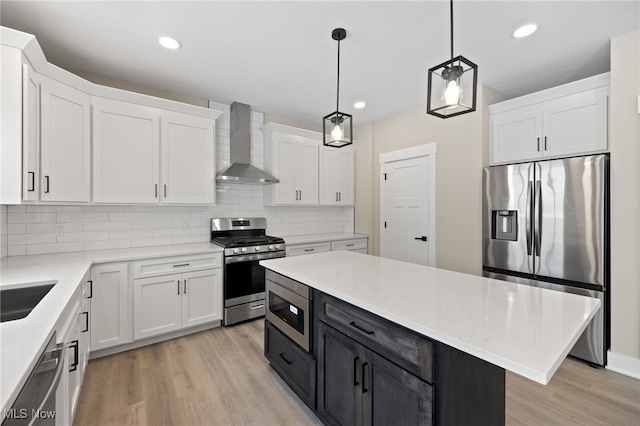 kitchen featuring light countertops, hanging light fixtures, appliances with stainless steel finishes, white cabinets, and wall chimney exhaust hood