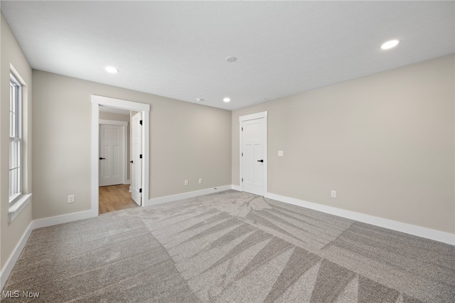 empty room with recessed lighting, light colored carpet, and baseboards