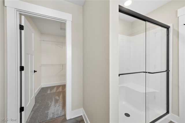 bathroom featuring a stall shower, a spacious closet, and baseboards