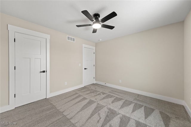 empty room featuring carpet floors, a ceiling fan, visible vents, and baseboards