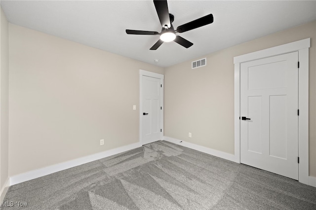 carpeted spare room featuring baseboards, visible vents, and a ceiling fan