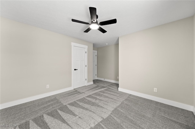 spare room featuring carpet floors, a ceiling fan, and baseboards