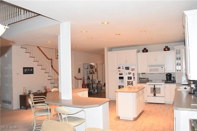 kitchen with glass insert cabinets, white appliances, white cabinets, and a kitchen island