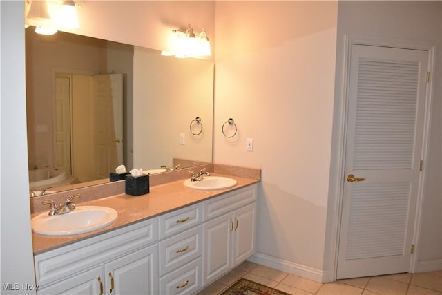 full bath featuring double vanity, a sink, baseboards, and tile patterned floors