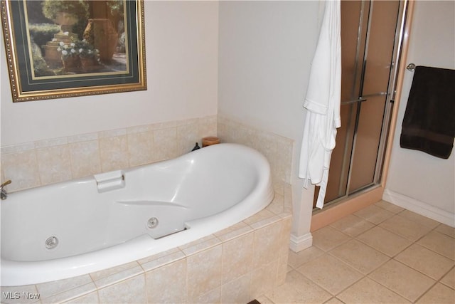 bathroom with a relaxing tiled tub, a shower stall, and tile patterned floors