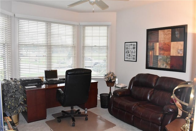 home office with a ceiling fan and light carpet