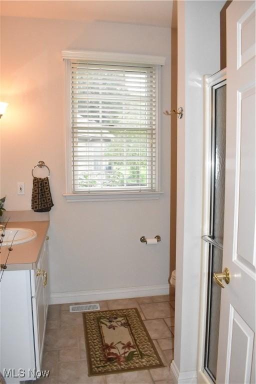 full bathroom with a shower with door, visible vents, toilet, vanity, and tile patterned flooring