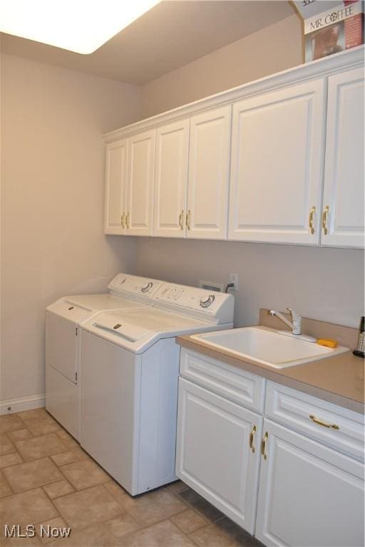 washroom featuring baseboards, a sink, cabinet space, and washer and dryer
