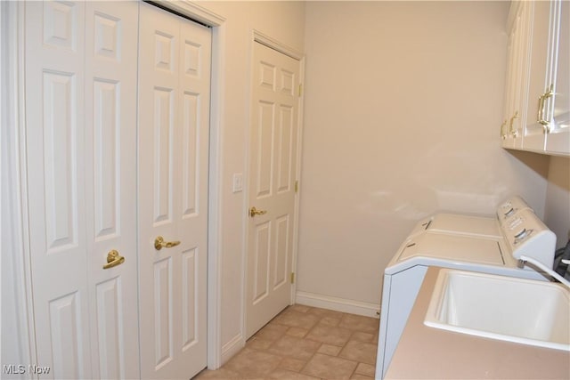 laundry area featuring a sink, baseboards, independent washer and dryer, cabinet space, and stone finish flooring