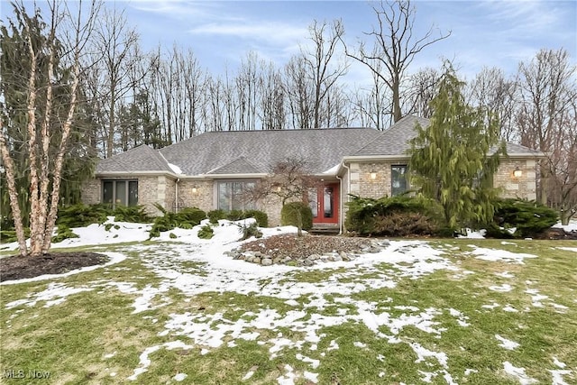 view of front of home featuring a shingled roof, brick siding, and a lawn