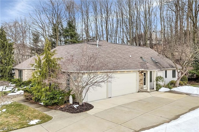 single story home with a garage, driveway, roof with shingles, and stone siding