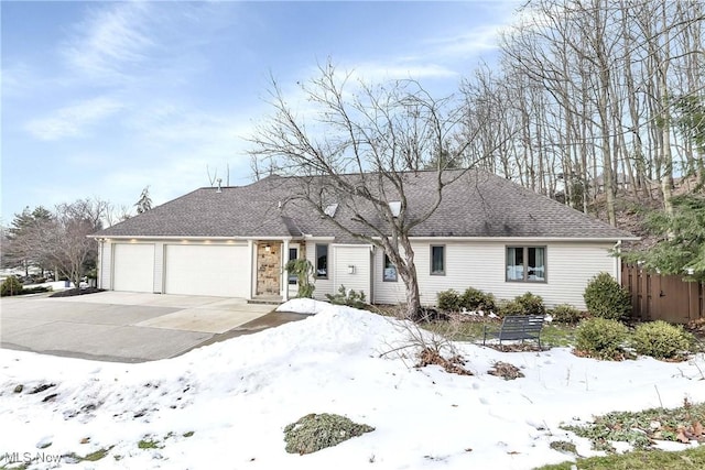 ranch-style house with an attached garage, a shingled roof, and concrete driveway