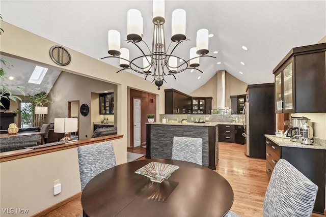 dining room featuring a chandelier, lofted ceiling with skylight, recessed lighting, and light wood-style floors