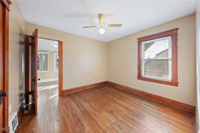 unfurnished room with ceiling fan, wood-type flooring, visible vents, and baseboards