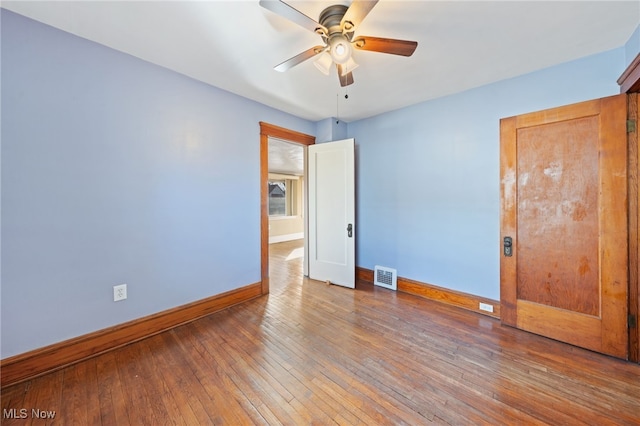 empty room featuring a ceiling fan, baseboards, visible vents, and hardwood / wood-style floors