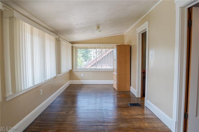 empty room featuring lofted ceiling, dark wood finished floors, visible vents, and baseboards