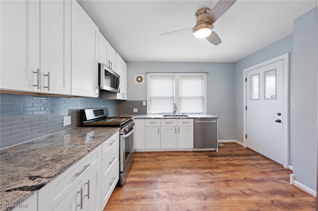 kitchen featuring light stone counters, backsplash, appliances with stainless steel finishes, white cabinets, and wood finished floors