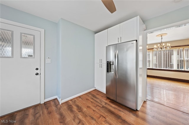 kitchen with dark wood-type flooring, white cabinetry, baseboards, hanging light fixtures, and stainless steel refrigerator with ice dispenser