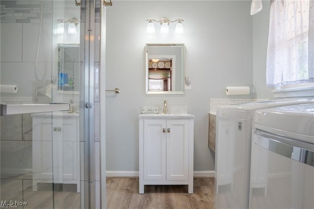 bathroom featuring washer / clothes dryer, a shower stall, vanity, wood finished floors, and baseboards