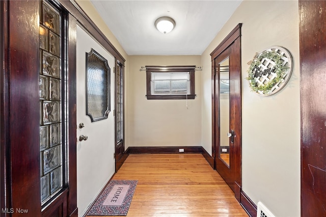 doorway to outside with light wood-style floors, visible vents, and baseboards