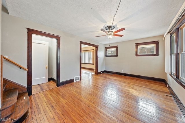 interior space with light wood-style floors, baseboards, visible vents, and a textured ceiling