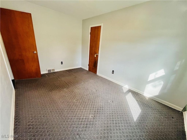 unfurnished bedroom featuring dark colored carpet, visible vents, and baseboards