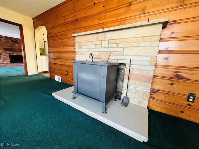 details with arched walkways, carpet, wood walls, and a stone fireplace