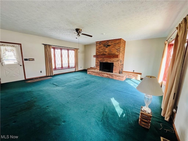 unfurnished living room featuring baseboards, ceiling fan, carpet, a textured ceiling, and a brick fireplace