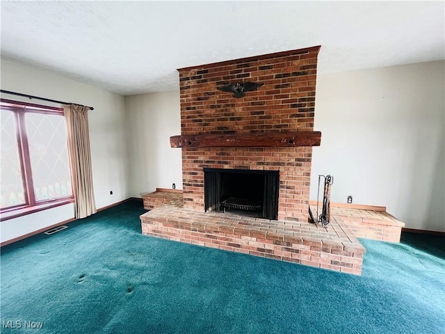 unfurnished living room with carpet floors, a fireplace, visible vents, and baseboards