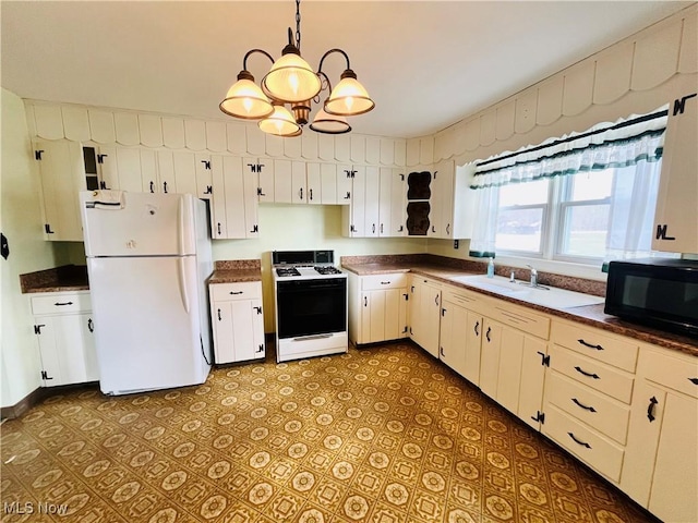 kitchen featuring white appliances, a sink, white cabinetry, dark countertops, and pendant lighting