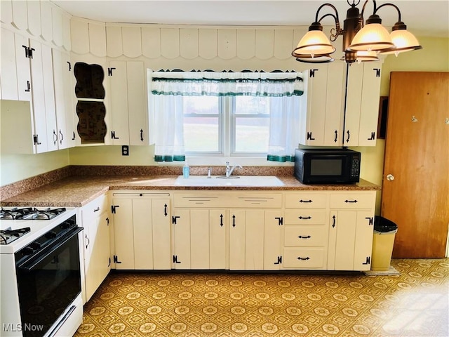 kitchen featuring white cabinets, hanging light fixtures, black microwave, a sink, and gas stove