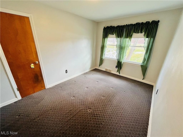 empty room with carpet floors, baseboards, and visible vents