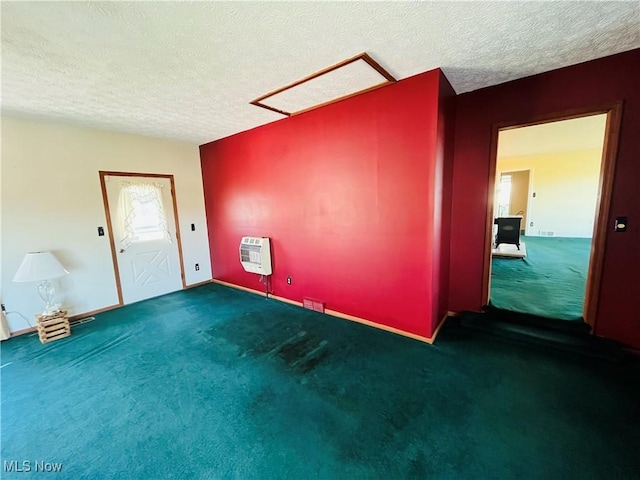 spare room featuring a textured ceiling, dark colored carpet, and heating unit