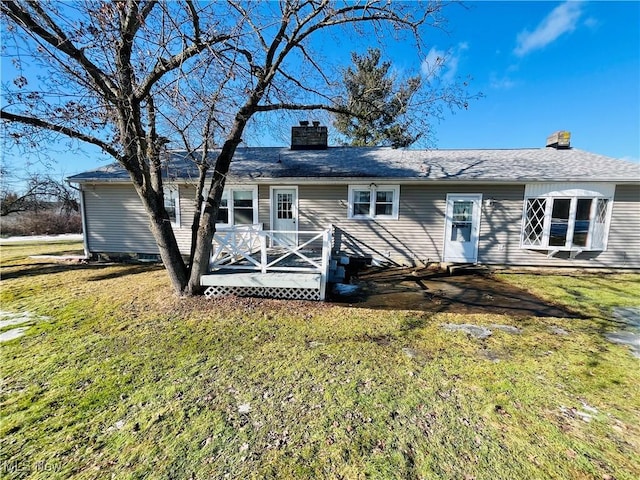 back of house with a wooden deck, a chimney, and a yard