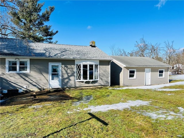 rear view of house with a yard and a shingled roof