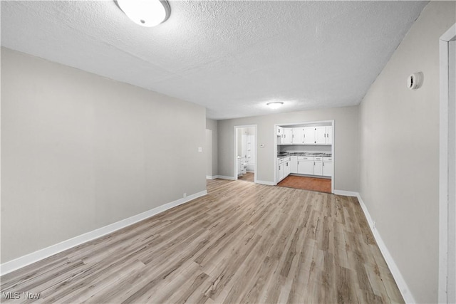 unfurnished living room featuring light wood-style floors, baseboards, and a textured ceiling