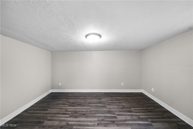 spare room featuring a textured ceiling, baseboards, and dark wood-type flooring