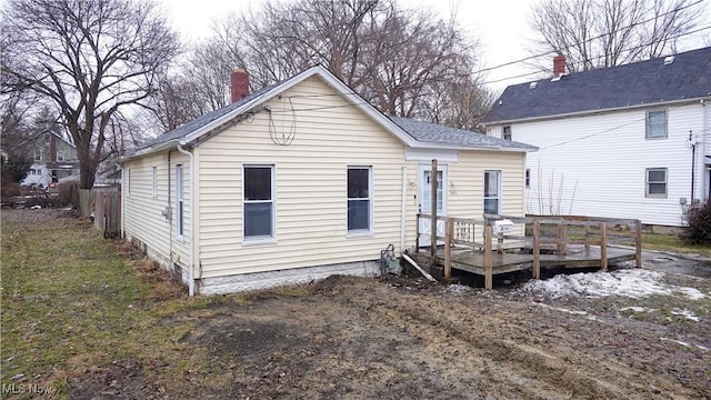 rear view of house featuring a chimney, fence, and a deck