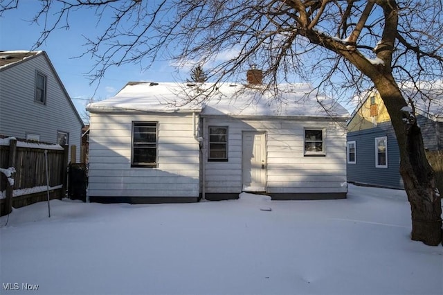 snow covered house featuring fence