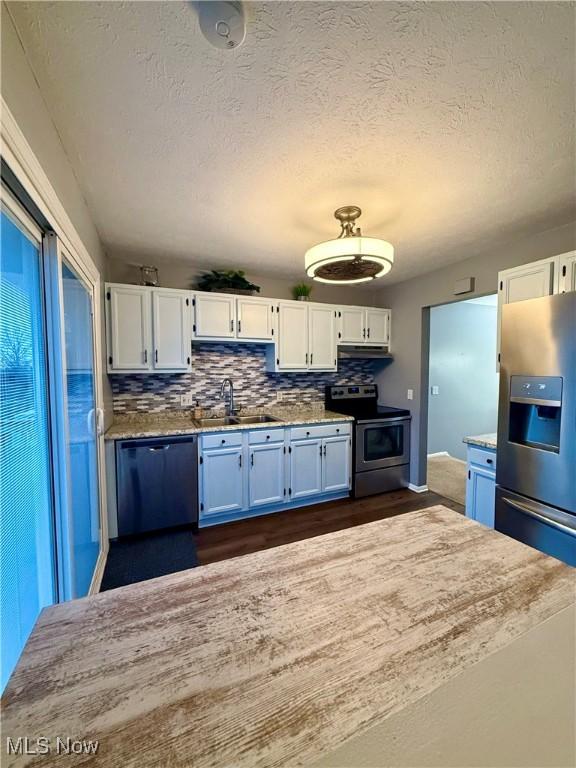 kitchen featuring backsplash, white cabinetry, stainless steel appliances, and a sink