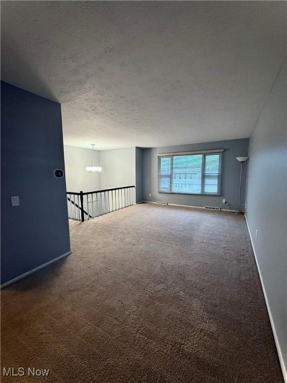 spare room featuring carpet flooring, a textured ceiling, and baseboards