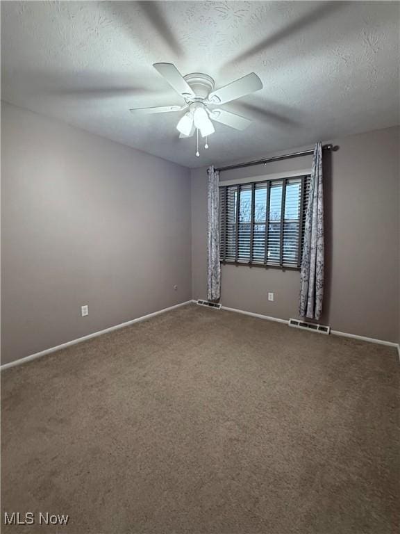 carpeted empty room with a ceiling fan, visible vents, a textured ceiling, and baseboards