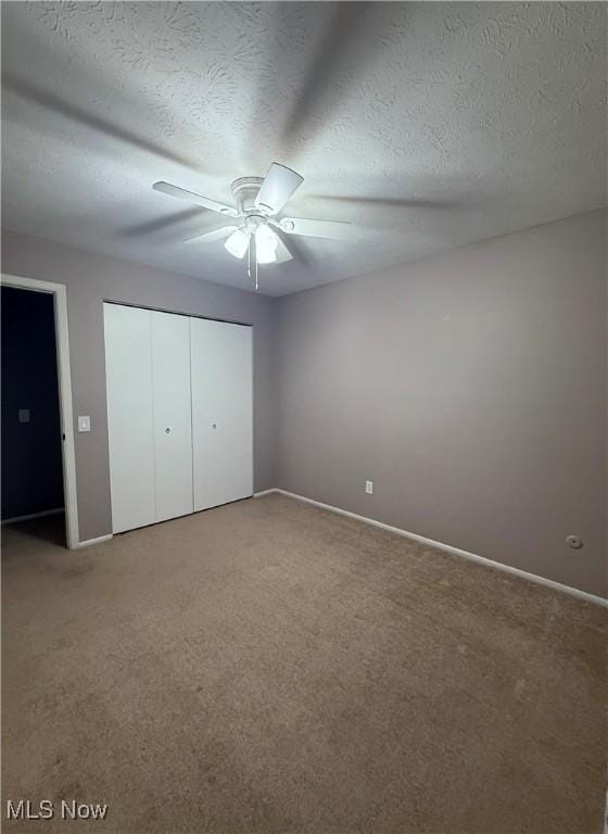 unfurnished bedroom with a textured ceiling, a closet, carpet flooring, and a ceiling fan