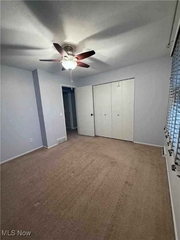 unfurnished bedroom with ceiling fan, a textured ceiling, carpet flooring, and baseboards