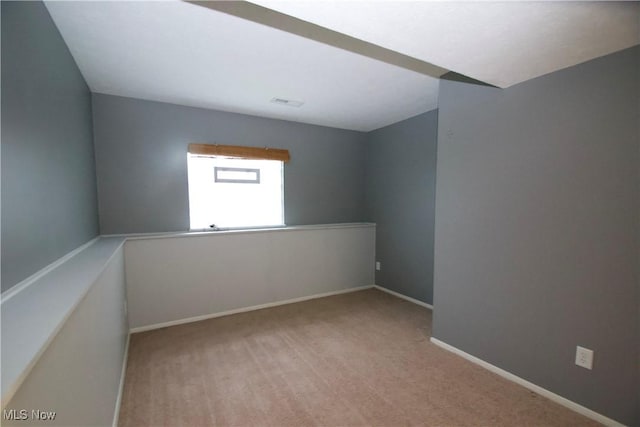 spare room featuring light carpet and baseboards